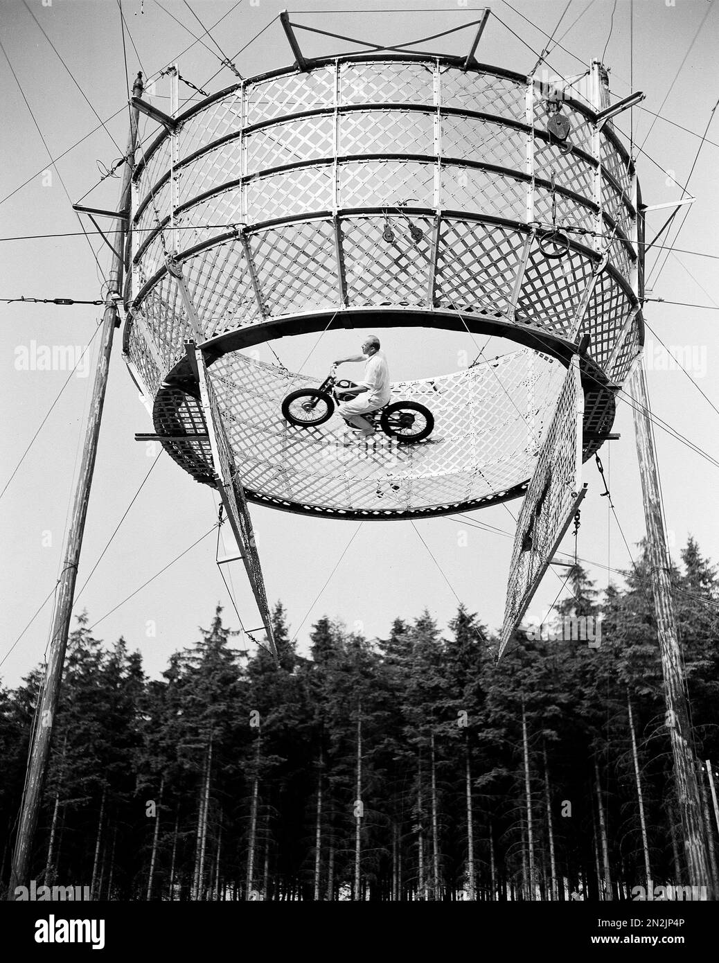 Motorcycle acrobat Richard Moltan rides on the "Highway of Death," 50 feet above a stunned audience, near Goslar, West Germany, July 6, 1952. The "highway" is an aluminum mesh cage that is six feet high and 15 feet in diameter. The gates, or "floor", on which the rider gets his start, open after he picks up enough speed. Moltan, who began his hair raising career in 1930, is back after a 10-year lapse caused by the destruction of his equipment during World War II. (AP Photo/Henry Brueggemann) Banque D'Images