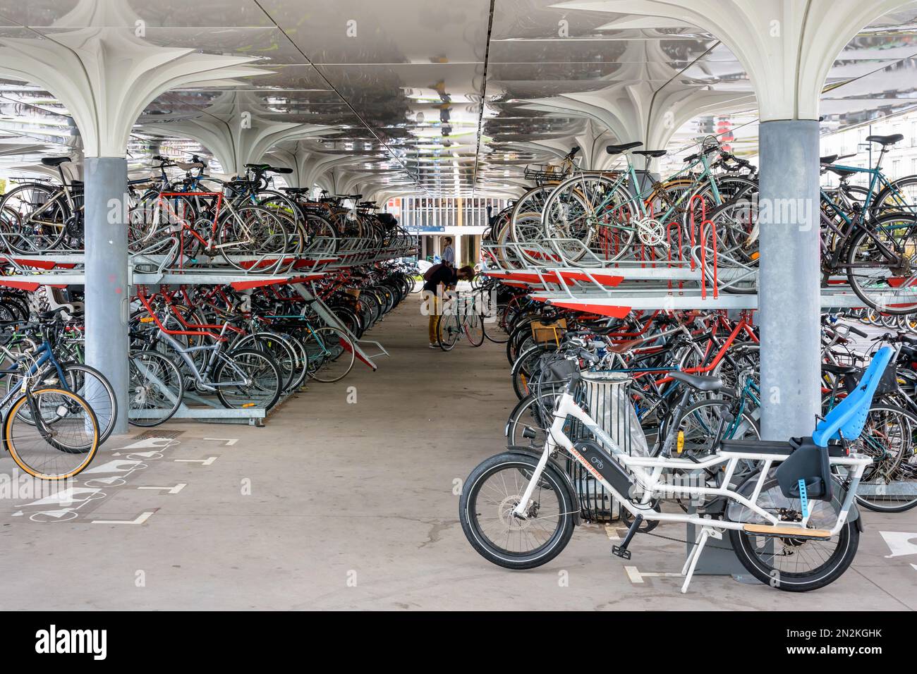 Des centaines de vélos sont garés dans un parking couvert à deux ponts à l'extérieur de la gare de Nantes, en France, pendant la journée. Banque D'Images
