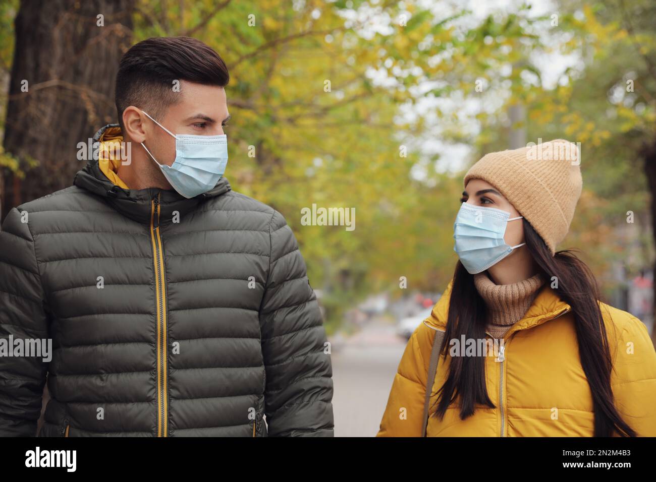 Couple dans les masques médicaux de visage marchant à l'extérieur. Protection personnelle pendant la pandémie de COVID-19 Banque D'Images