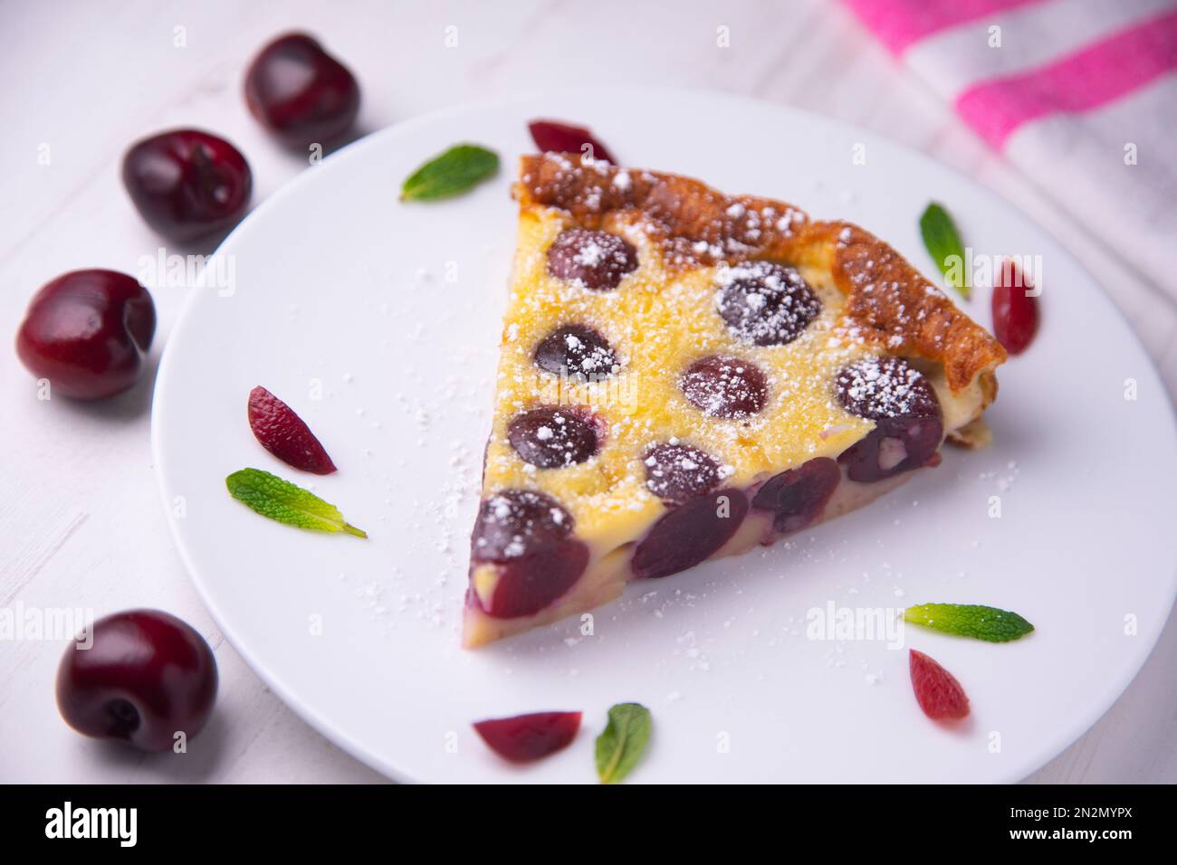 La clafoutis de cerise est un dessert de fruits français cuit au four, des cerises noires traditionnelles, disposées sur une assiette beurrée et recouverte d'une épaisse chauve-souris semblable à une crème anglaise Banque D'Images