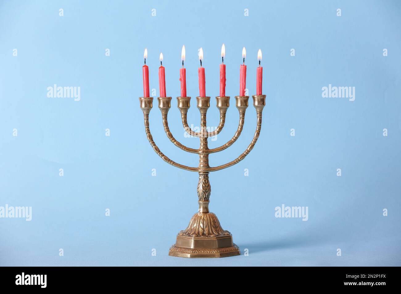Menorah dorée avec bougies allumées sur fond bleu clair Banque D'Images