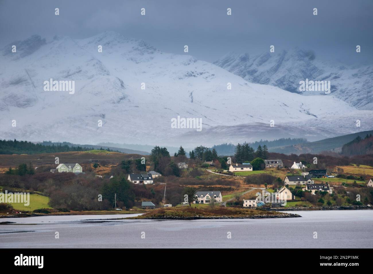 Écosse, île de Skye, village en hiver avec des cottages de crofters blancs, des montagnes enneigées et aucun peuple Banque D'Images