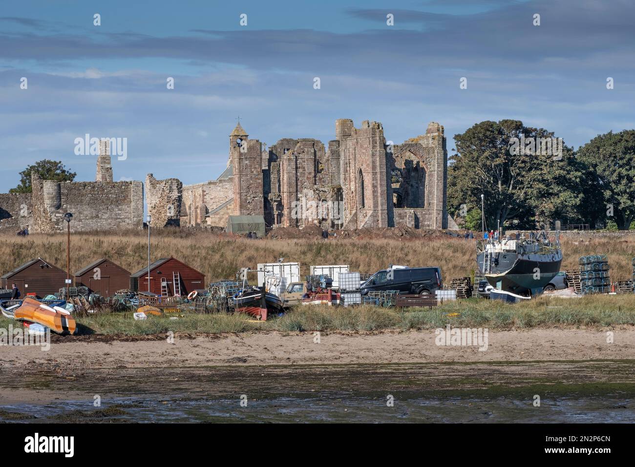 Lindisfarne, Northumberland, UK, vue d'été sur les ruines du Prieuré médiéval de Lindisfarne avec des bateaux en premier plan. Personne. Copier l'espace. Banque D'Images