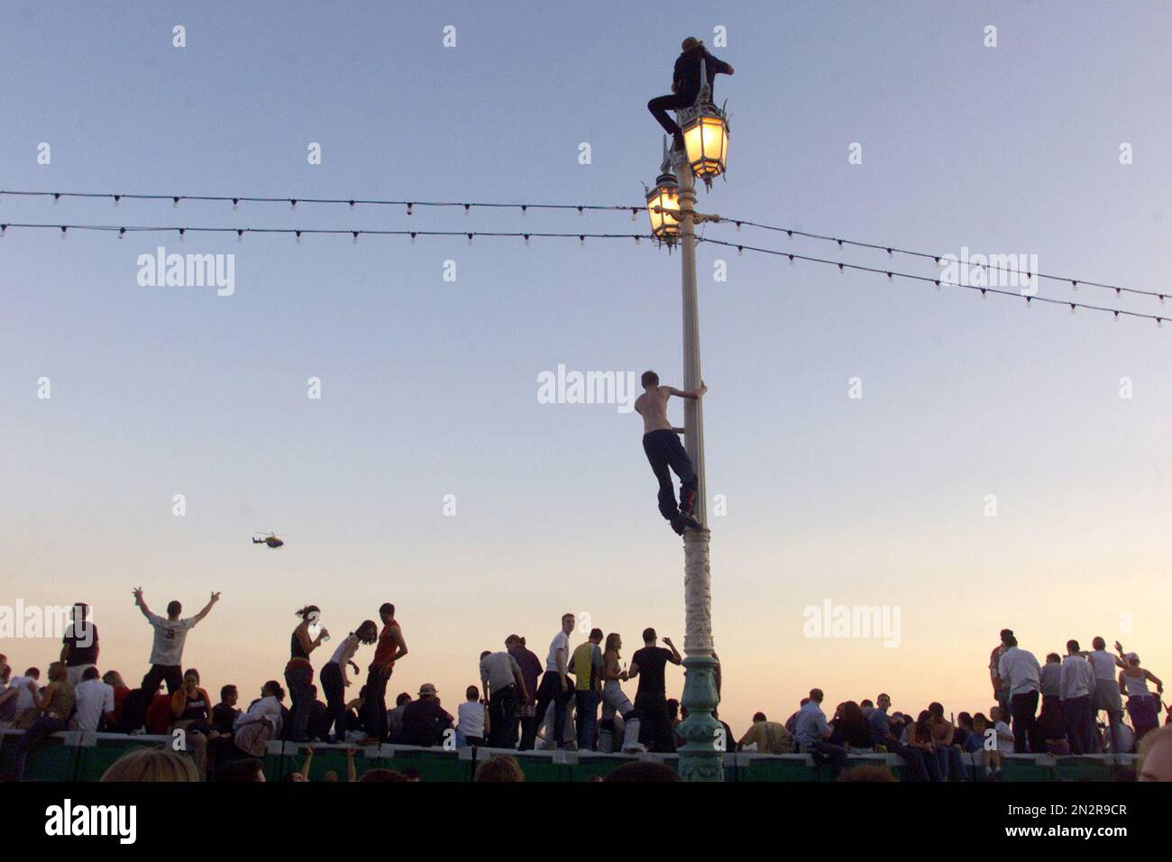 Les fêtards ont grimpé un lampost pour essayer d'obtenir un point de vue pour la Fatboy Slim Big Beach Boutique Party où une foule estimée à 200000 personnes est venue sur le front de mer de Brighton pour la soirée. Norman Cook le musicien de danse et DJ a organisé et payé pour la deuxième année . Photographie prise par Simon Dack juillet 2002 Banque D'Images