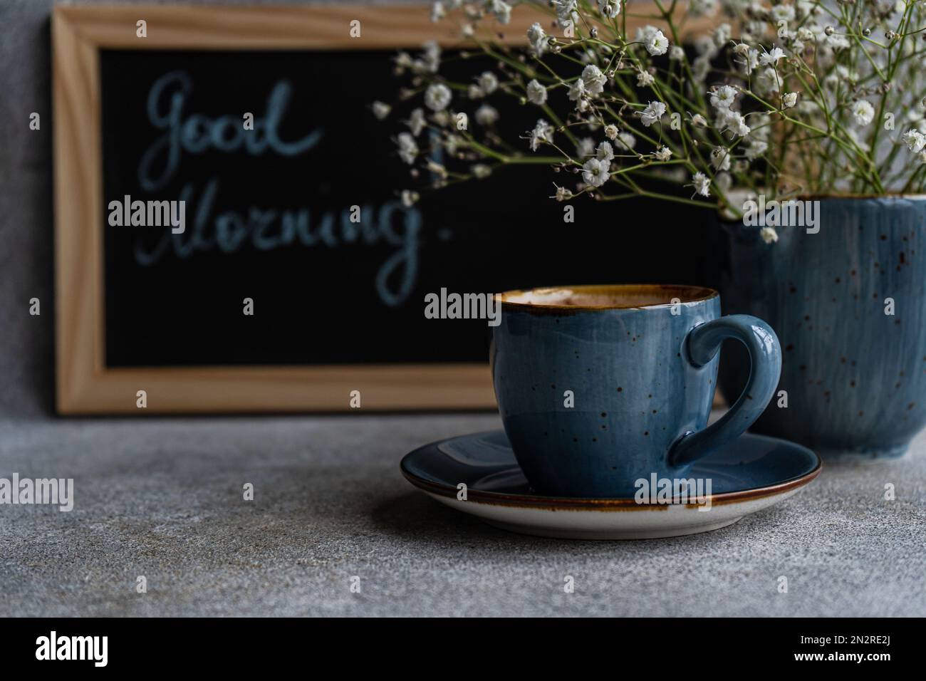 Un bouquet de fleurs blanches de Gypsophila et de cappuccino à côté d'un tableau noir avec les mots Bonjour Banque D'Images
