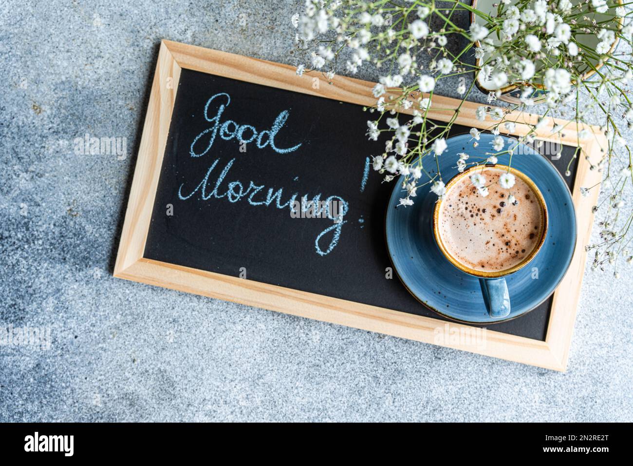 Vue en hauteur d'un bouquet de fleurs de Gypsophila blanches et de cappuccino à côté d'un tableau noir avec les mots Bonjour Banque D'Images