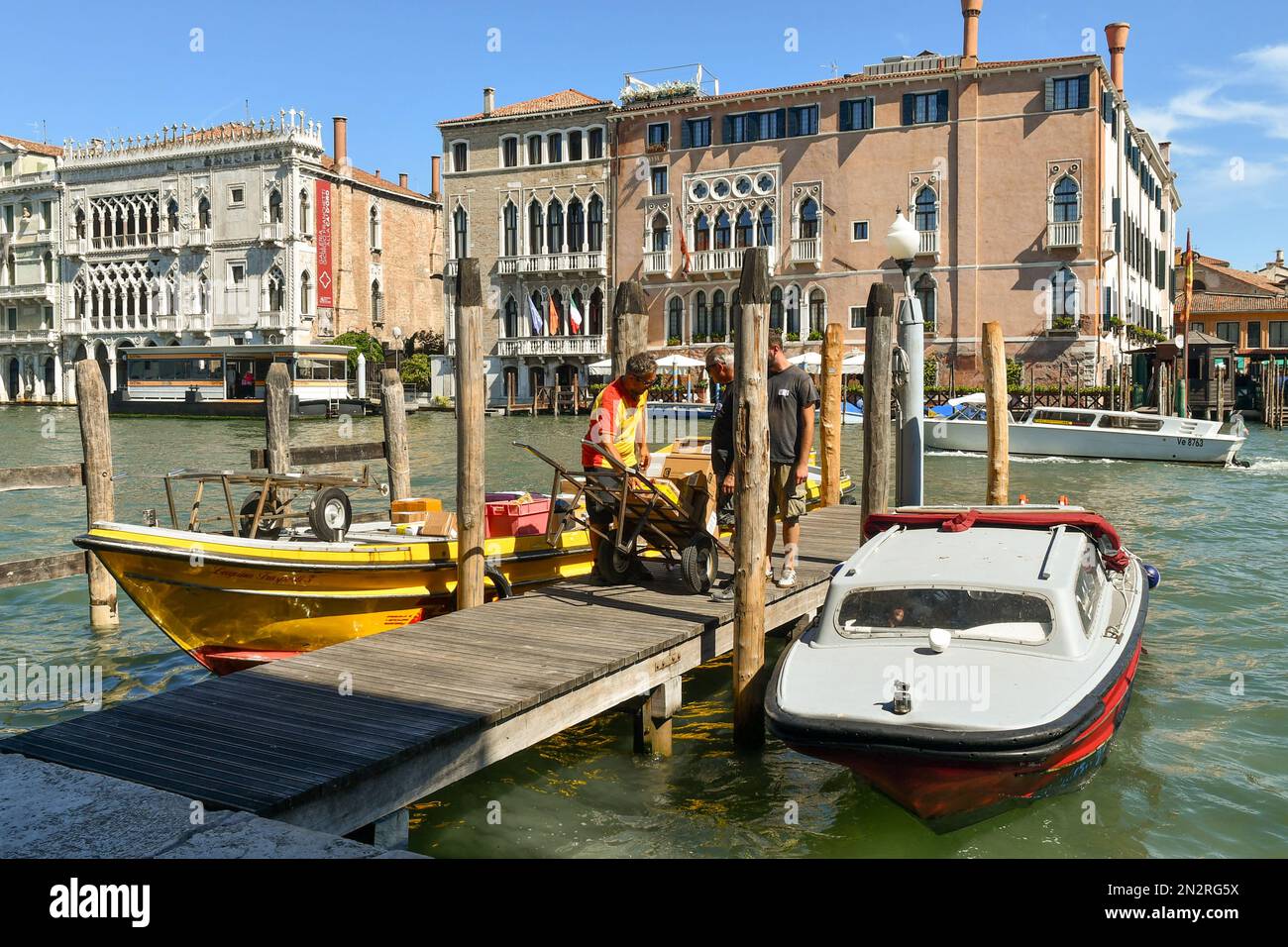 Un transporteur DHL amarré pour le déchargement de caisses sur le Grand Canal avec les palais Cà Sagredo et Cà d'Oro en arrière-plan, Venise, Vénétie, Italie Banque D'Images