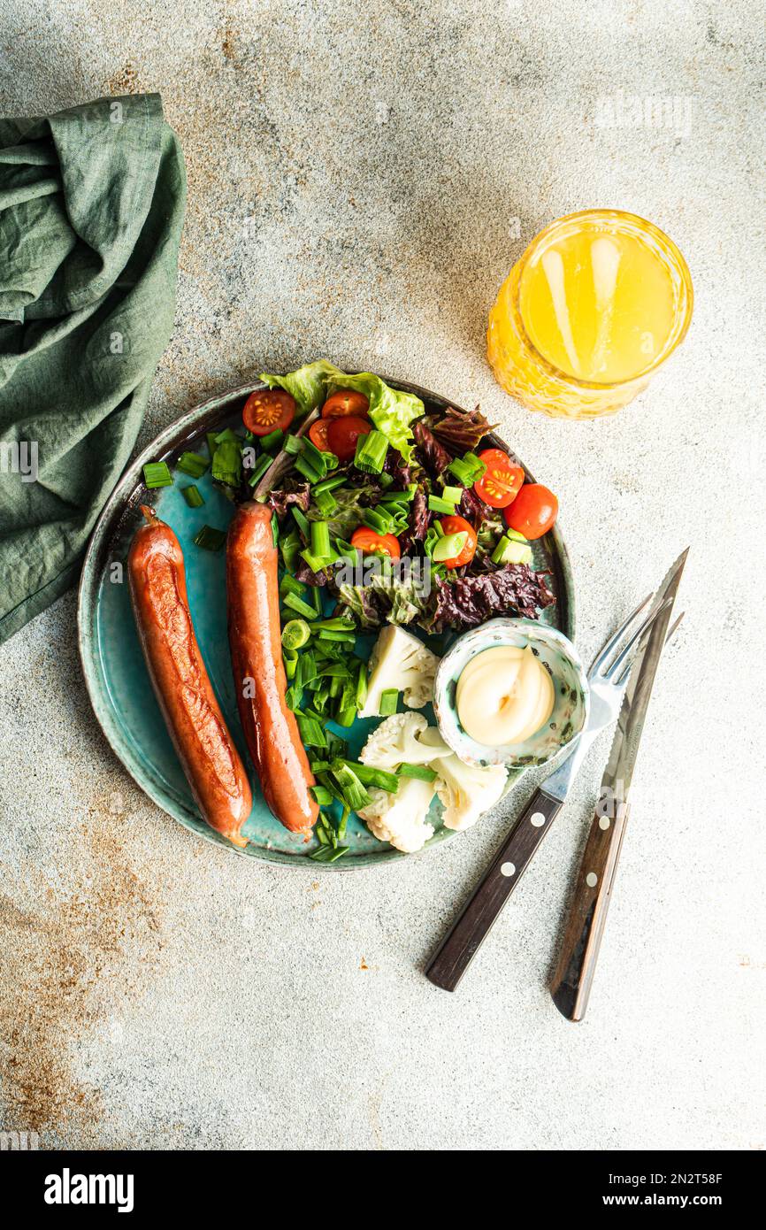 Vue en hauteur d'un œuf frit, saucisses, salade, mayonnaise et un verre de jus d'orange sur une table Banque D'Images