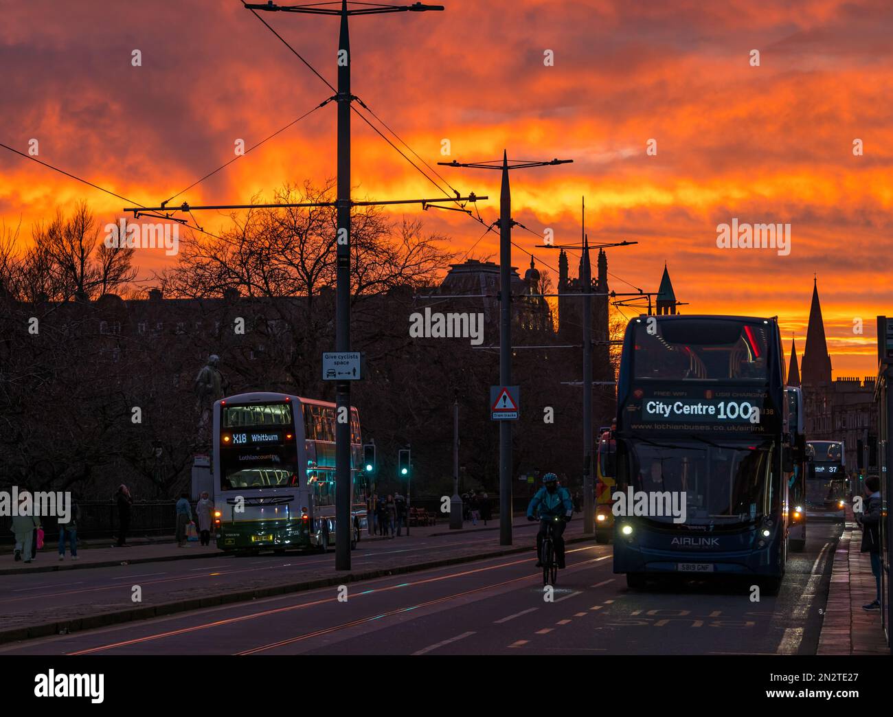 Coucher de soleil orange vif avec bus Lothian et bus Airlink au crépuscule, Princes Street, Édimbourg, Écosse, Royaume-Uni Banque D'Images