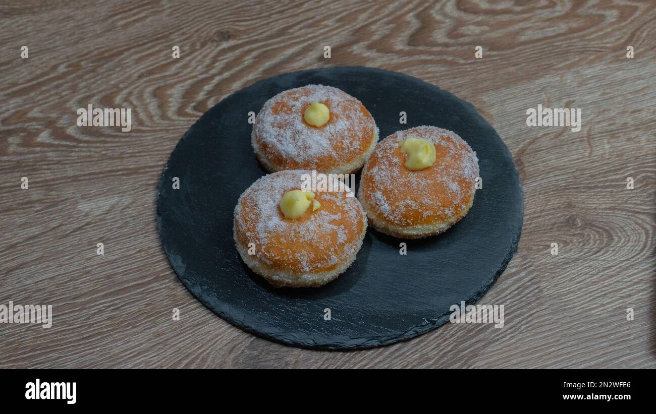 Beignets frits faits maison remplis de crème anglaise et assaisonnés d'un voile de sucre Banque D'Images