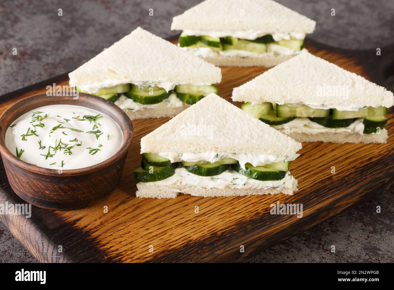 Les sandwichs au fromage à la crème et au concombre sont en gros plan sur le panneau en bois de la table. Horizontale Banque D'Images