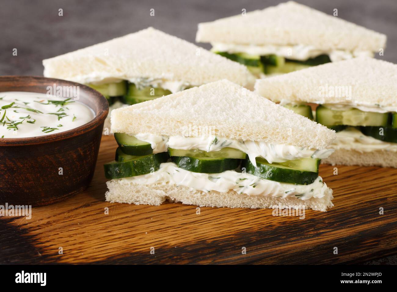 Les sandwichs au fromage à la crème au concombre sont en gros plan sur le panneau en bois de la table. Horizontale Banque D'Images