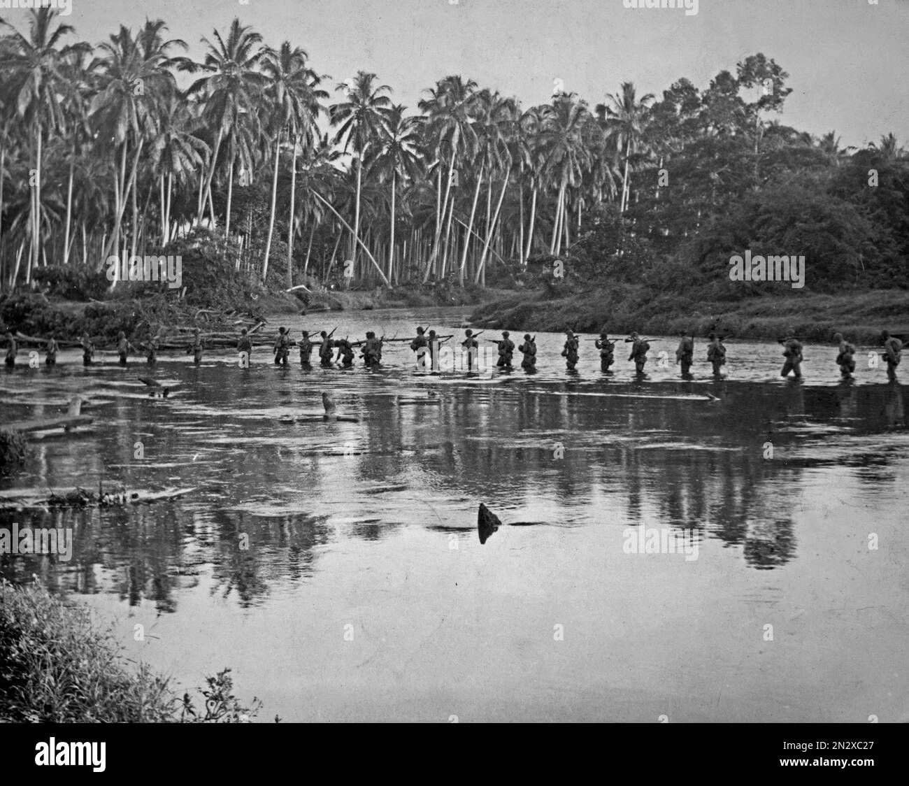 GUADALCANAL, ÎLES SALOMON - vers 1942-1943 - les Marines des États-Unis traversent un plan d'eau lors d'une patrouille en soirée pendant la bataille de Guadalcanal dans les Salomon Banque D'Images