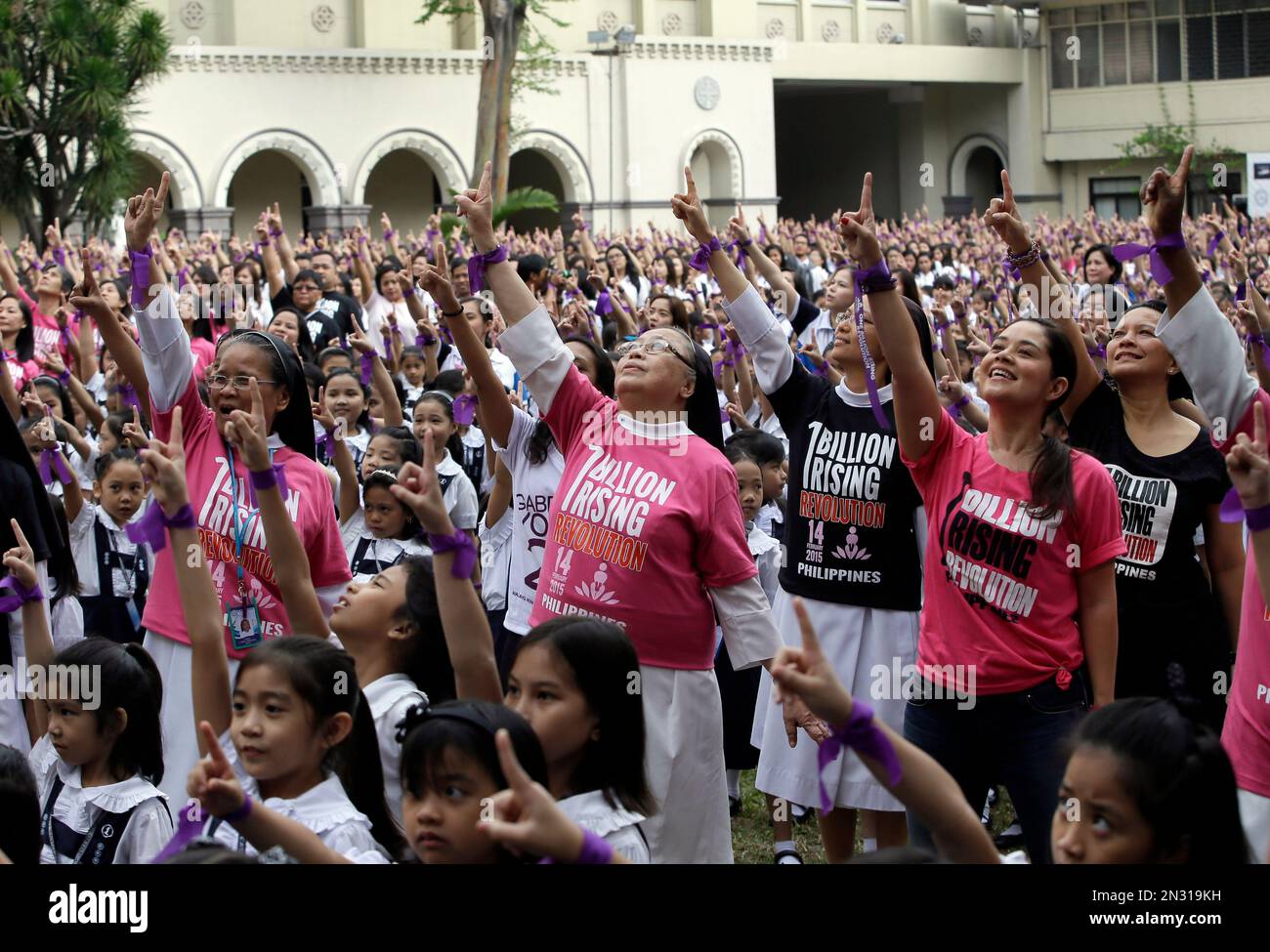 With purple ribbons on their wrists, more than 3,000 students, teachers and nuns from the Catholic-run St. Scholastica's College in Manila, flash the No.1 sign as they dance at their quadrangle to take part in the global campaign to end violence against women and girls dubbed One Billion Rising, Friday, Feb. 13, 2015 in Manila, Philippines. (AP Photo/Bullit Marquez) Banque D'Images