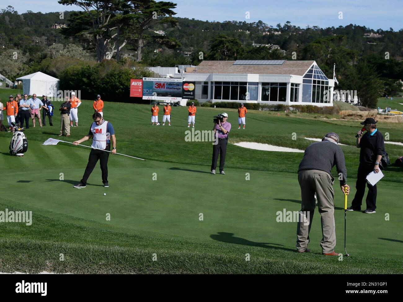 Actor Clint Eastwood putts on the 17th green of the Pebble Beach Golf Links as his caddie Nick Faldo tends the pin during the celebrity challenge event of the AT&T Pebble Beach National Pro-Am golf tournament Wednesday, Feb. 11, 2015, in Pebble Beach, Calif. (AP Photo/Eric Risberg) Banque D'Images