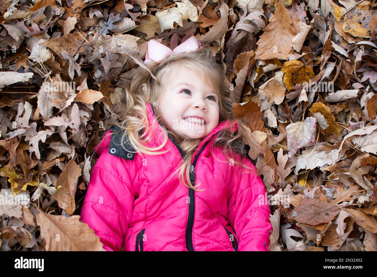 Enfant heureux dans le parc. Petite fille souriante dans les feuilles. Profitez de l'automne chaud. Banque D'Images