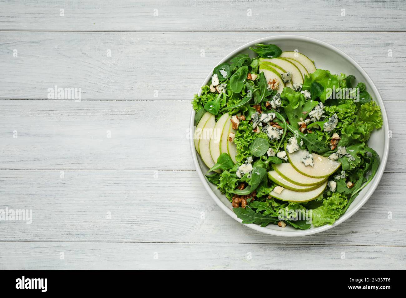 Salade fraîche avec poire sur table en bois blanc, vue sur le dessus. Espace pour le texte Banque D'Images