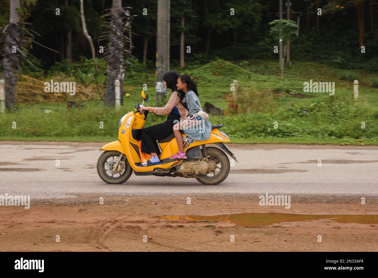 Mère et fille à bord d'une moto à la campagne. Ko Lanta, Krabi, Thaïlande. 4 décembre 2022. Banque D'Images