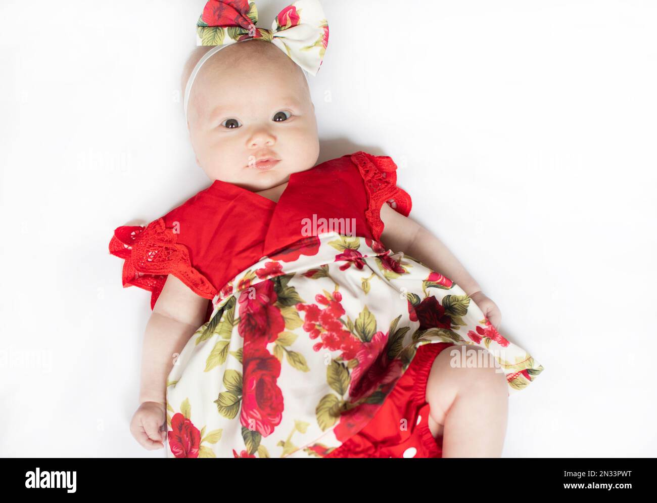 Portrait d'un petit bébé caucasien nouveau-né dans une robe rouge. bébé de 3 mois Banque D'Images