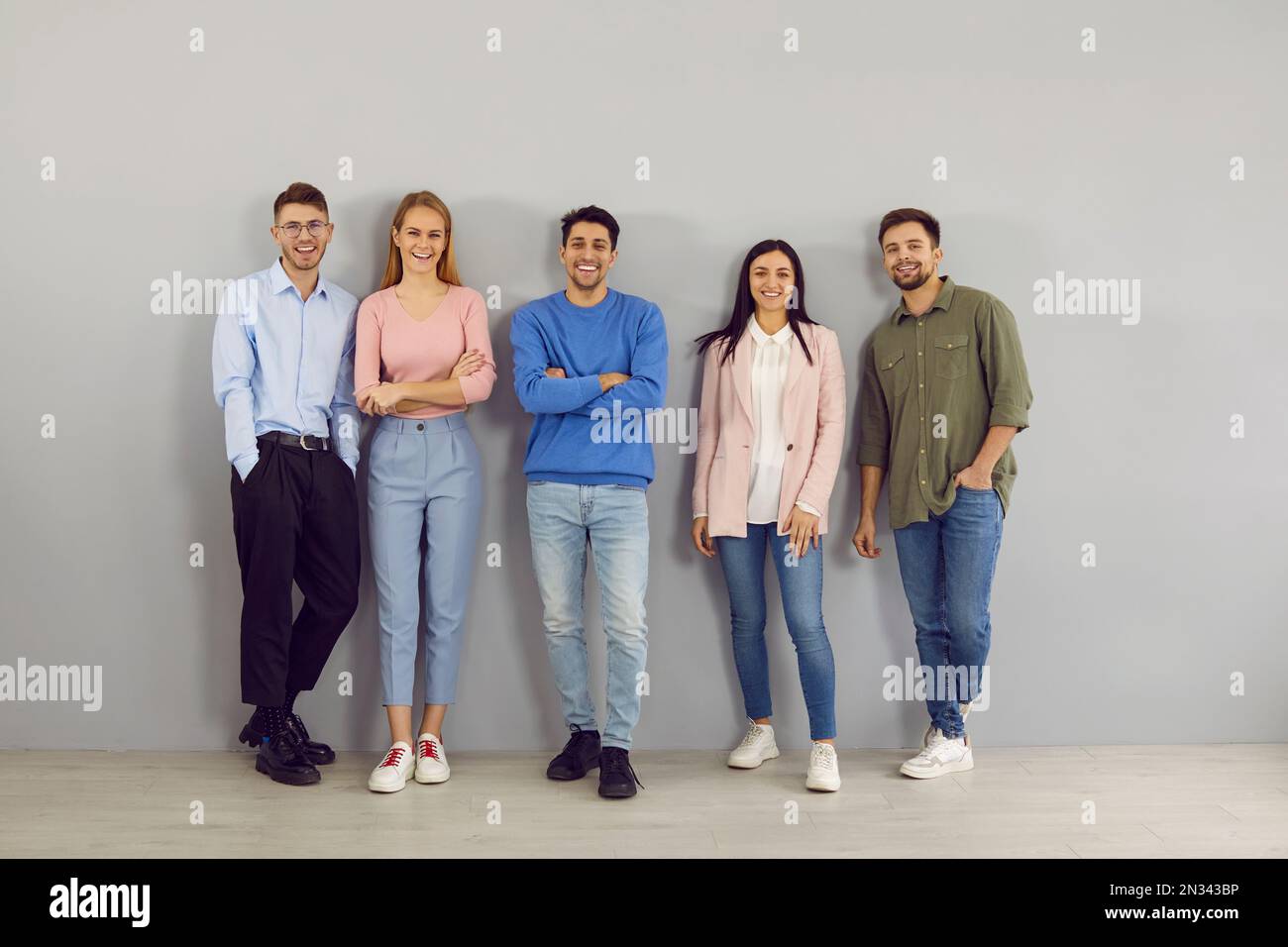 Portrait d'un groupe de jeunes intelligents positifs différents sur fond de mur gris. Banque D'Images