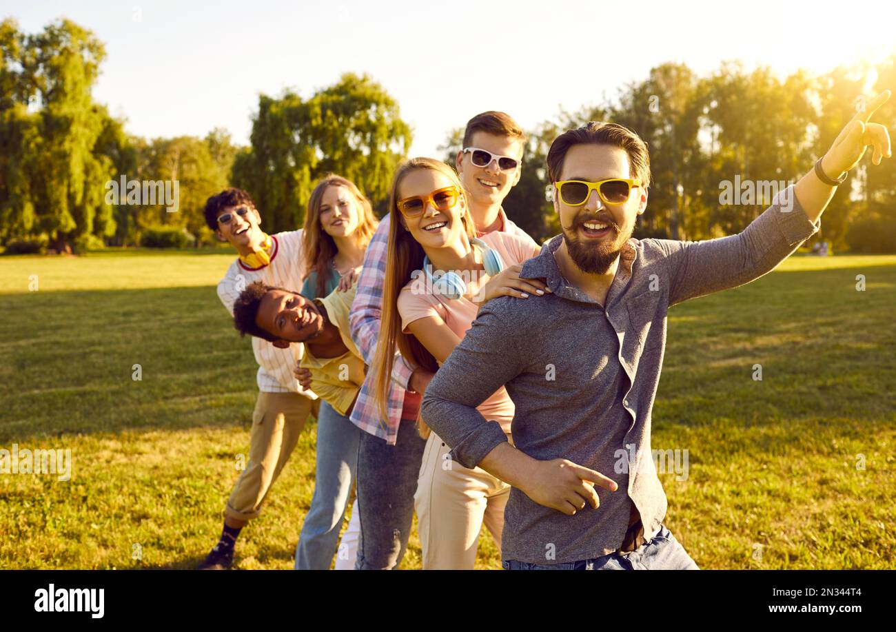 Drôle et joyeux compagnie joyeuse de jeunes amis ont plaisir ensemble sur la pelouse verte dans le parc. Banque D'Images