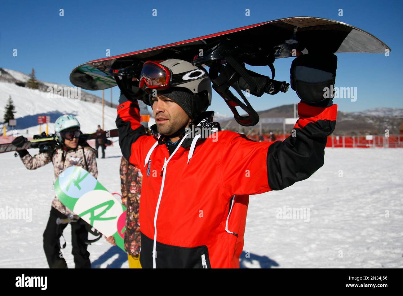 Actor and producer Adrian Grenier, right, carries his snowboard on his head as he makes his way to the lift at Park City Mountain Resort during the 2015 Sundance Film Festival on Monday, Jan. 26, 2015, in Park City, Utah. While celebrities are consistently swarmed by fans at the Sundance Film Festival, there's one place they can find anonymity: On the slopes, which are empty as most out-of-towners are holed up in screenings. (Photo by Danny Moloshok/Invision/AP) Banque D'Images