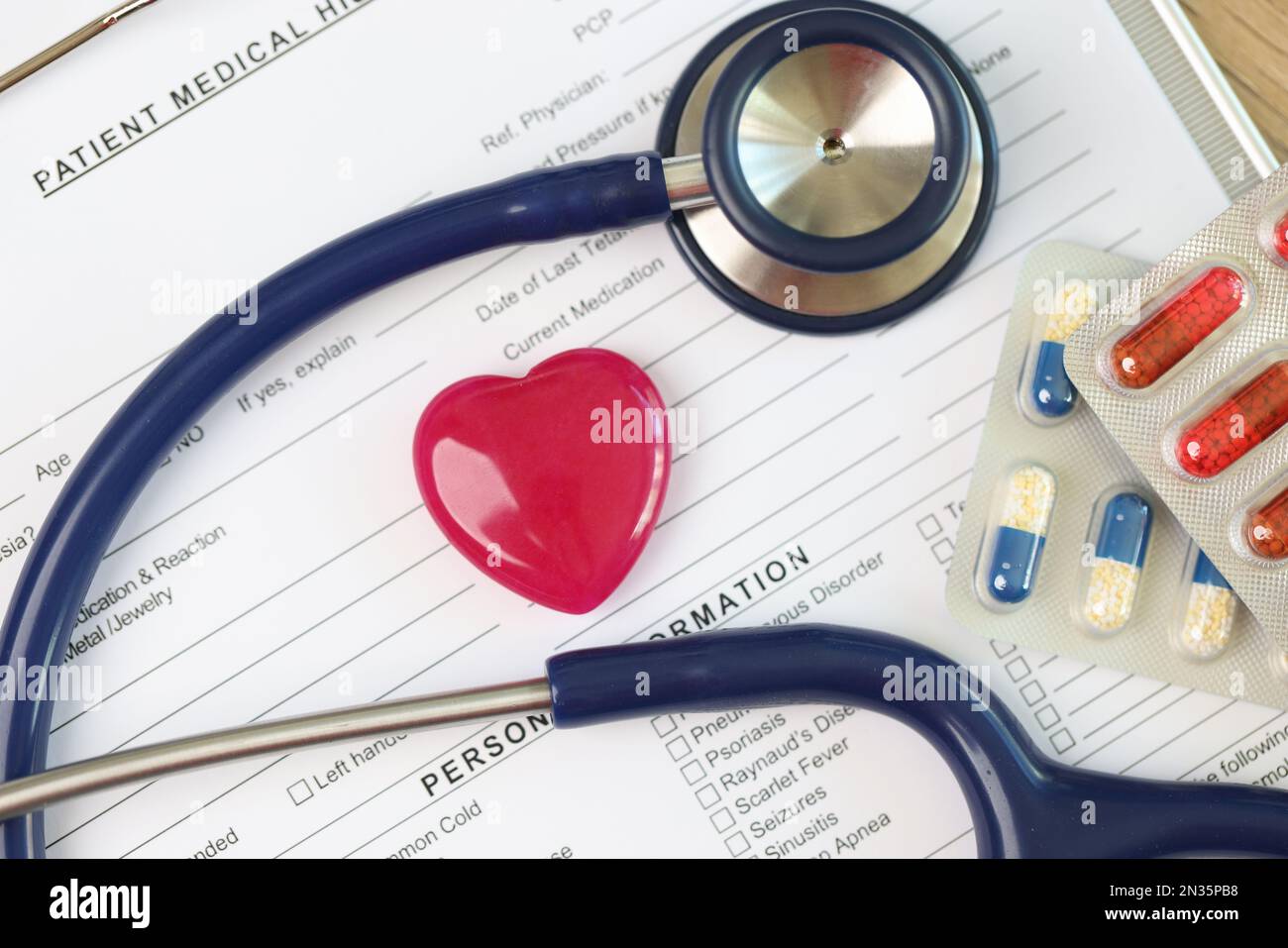 Les antécédents médicaux du patient se forment avec le cœur rouge, le stéthoscope et les paquets de pilules gros plan. Banque D'Images