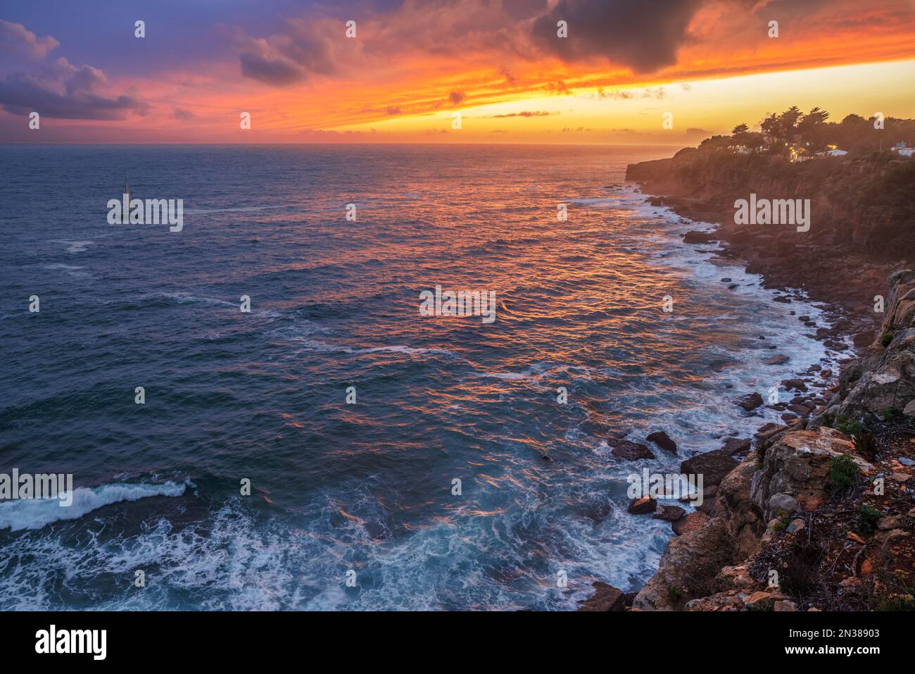 Coucher de soleil rouge coloré et ciel spectaculaire vif sur la rive rocheuse de l'océan Atlantique. Banque D'Images