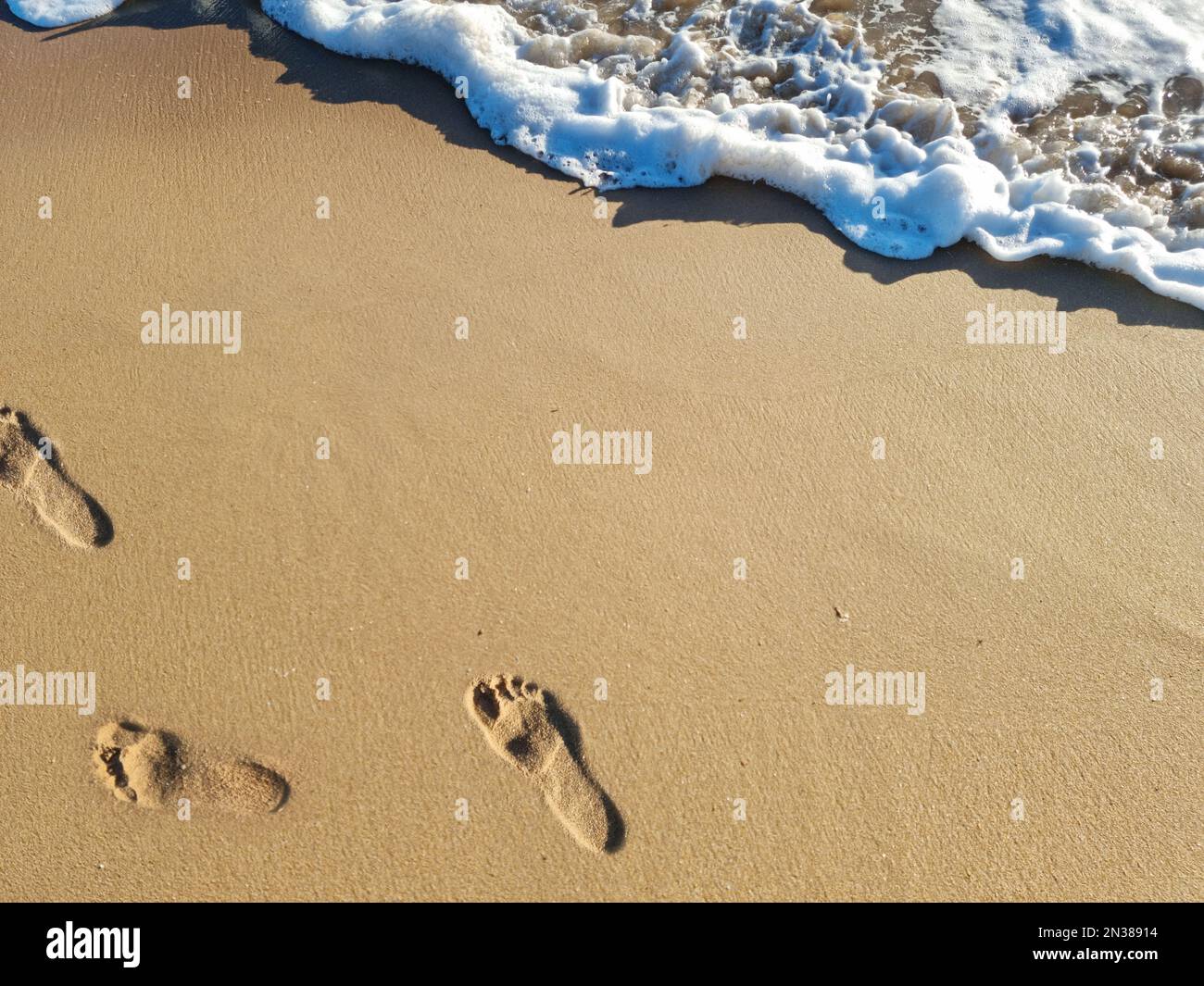Empreintes de pieds sur la plage de sable de l'océan. Vue de dessus. Banque D'Images