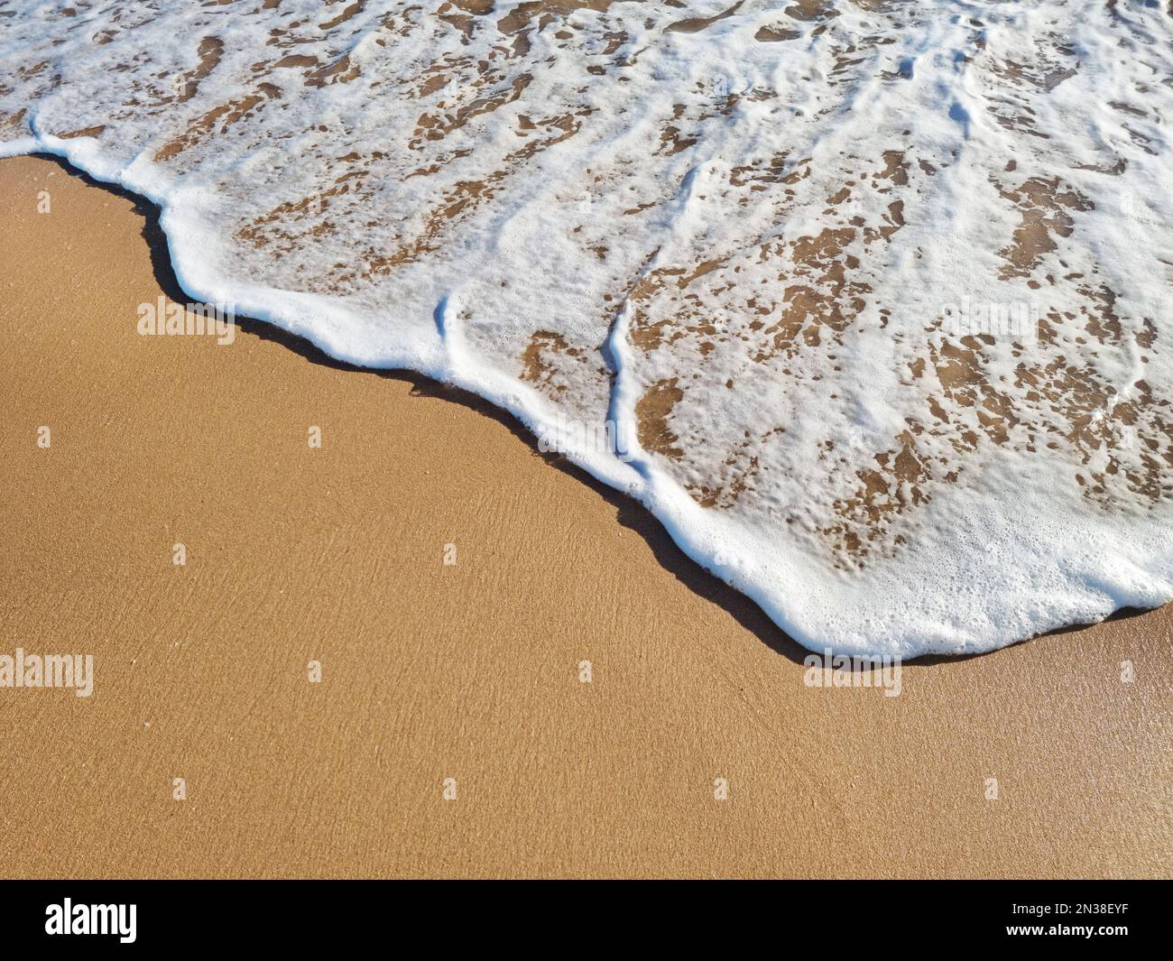 Mousse d'océan couvrant une belle plage de sable. Vue de dessus. Banque D'Images