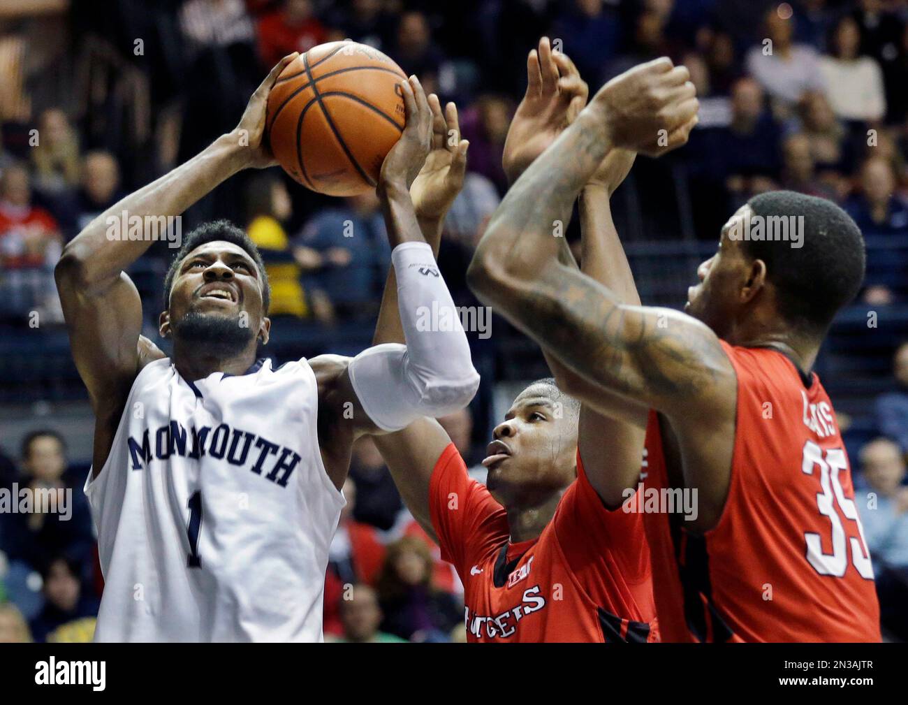 Monmouth's Brice Kofane, left, of Cameroon, takes a shot past Rutgers' Junior Etou, center, of from the Republic of Congo, and Greg Lewis (35) during the first half of an NCAA college basketball game Sunday, Dec. 28, 2014, in West Long Branch, N.J. (AP Photo/Mel Evans) Banque D'Images