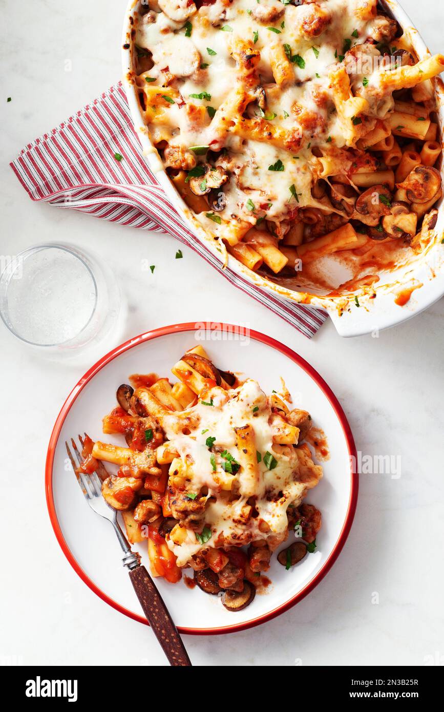 Ziti cuit avec des champignons dans une casserole avec une portion sur une assiette avec une fourchette devant Banque D'Images