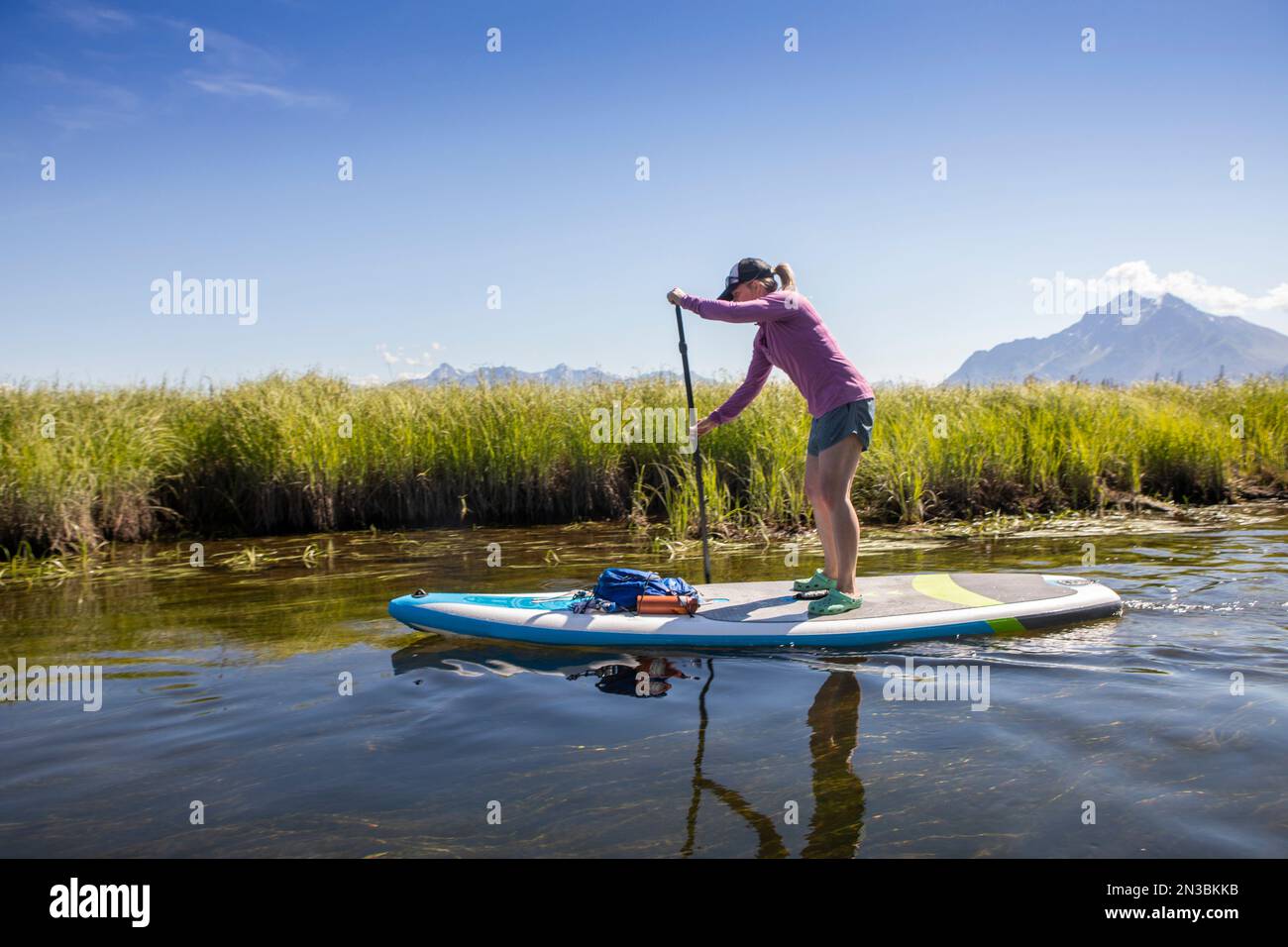 Femme caucasienne paddle board à Rabbit Slough, avec Pioneer Peak et Twin Peaks dans les montagnes Chugach en arrière-plan sur un... Banque D'Images