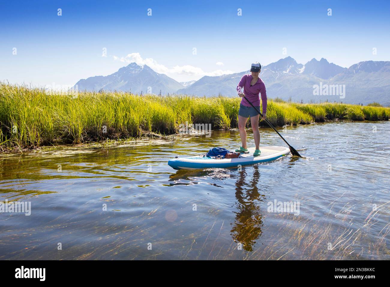 Femme caucasienne paddle board à Rabbit Slough, avec Pioneer Peak et Twin Peaks dans les montagnes Chugach en arrière-plan sur un... Banque D'Images