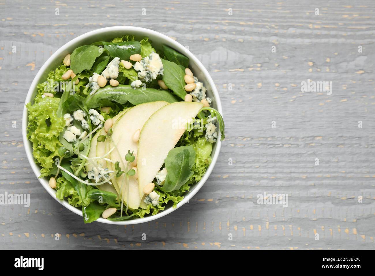 Salade fraîche avec poire sur table en bois gris, vue sur le dessus. Espace pour le texte Banque D'Images