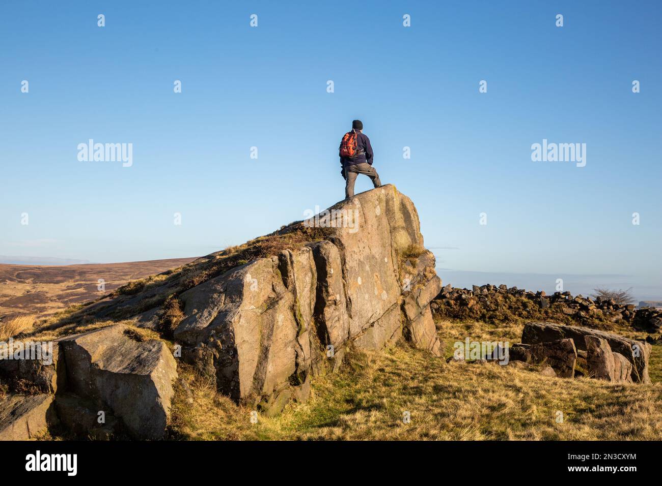 Homme debout sur la formation de roche sur Wolf Edge au-dessus du village de Flash dans le Staffordshire Moorlands Peak District Banque D'Images