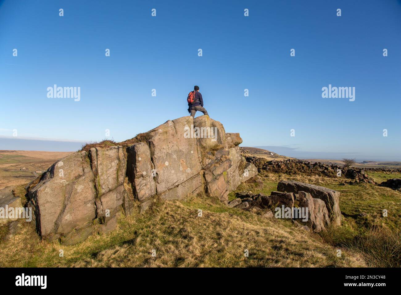 Homme debout sur la formation de roche sur Wolf Edge au-dessus du village de Flash dans le Staffordshire Moorlands Peak District Banque D'Images