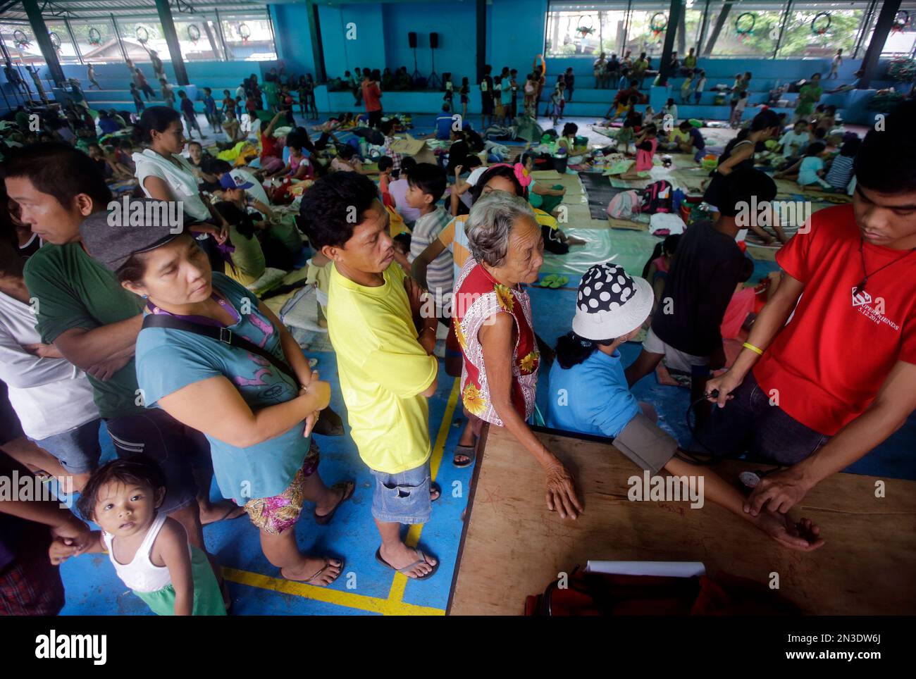 Residents, who fled their homes in anticipation of typhoon Hagupit, undergo medical check up at an evacuation center at suburban Quezon city northeast of Manila, Philippines Tuesday, Dec. 9, 2014. A storm that began as a frighteningly powerful typhoon started to blow away from the Philippines Tuesday, after leaving at least 21 people dead and forcing more than a million into shelters. (AP Photo/Bullit Marquez) Banque D'Images