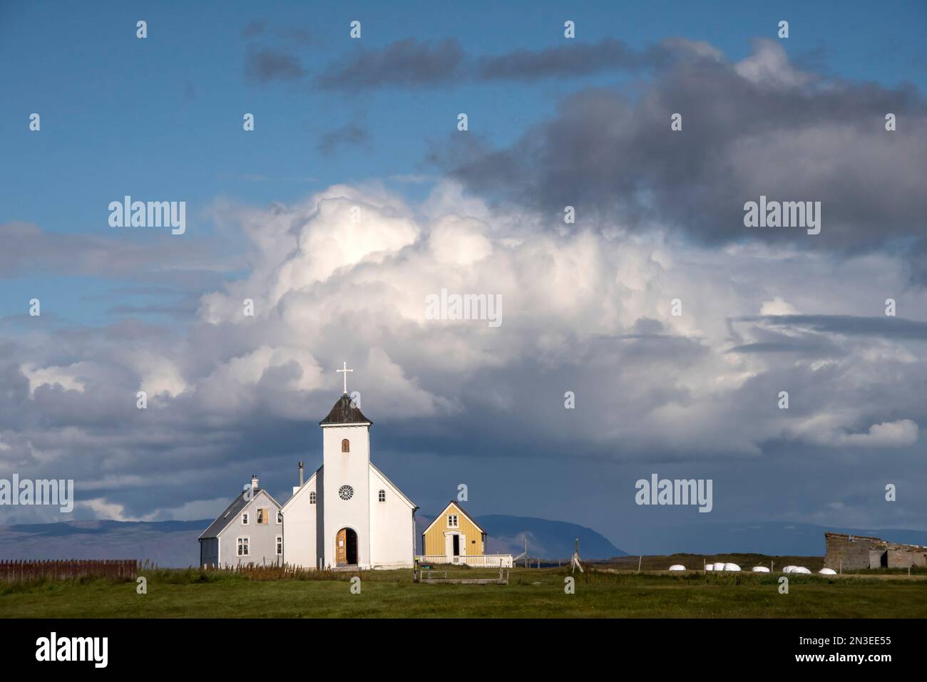 Église communautaire illuminée par le soleil avec un ciel nuageux au-dessus de Flatey Island, partie d'un groupe d'environ quarante grandes et petites îles et îlots L... Banque D'Images