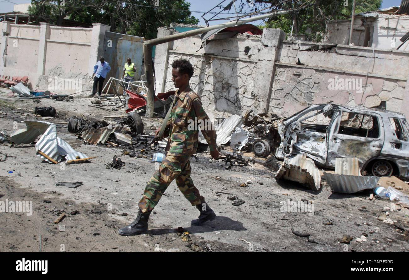 A Somali soldier walks near wreckage at the scene of a suicide car bomb attack that targeted a United Nations convoy, outside the airport in Mogadishu, Somalia Wednesday, Dec. 3, 2014. A Somali police officer says a suicide bomber rammed his vehicle into a U.N. convoy near Mogadishu's airport, killing three people. (AP Photo/Farah Abdi Warsameh) Banque D'Images