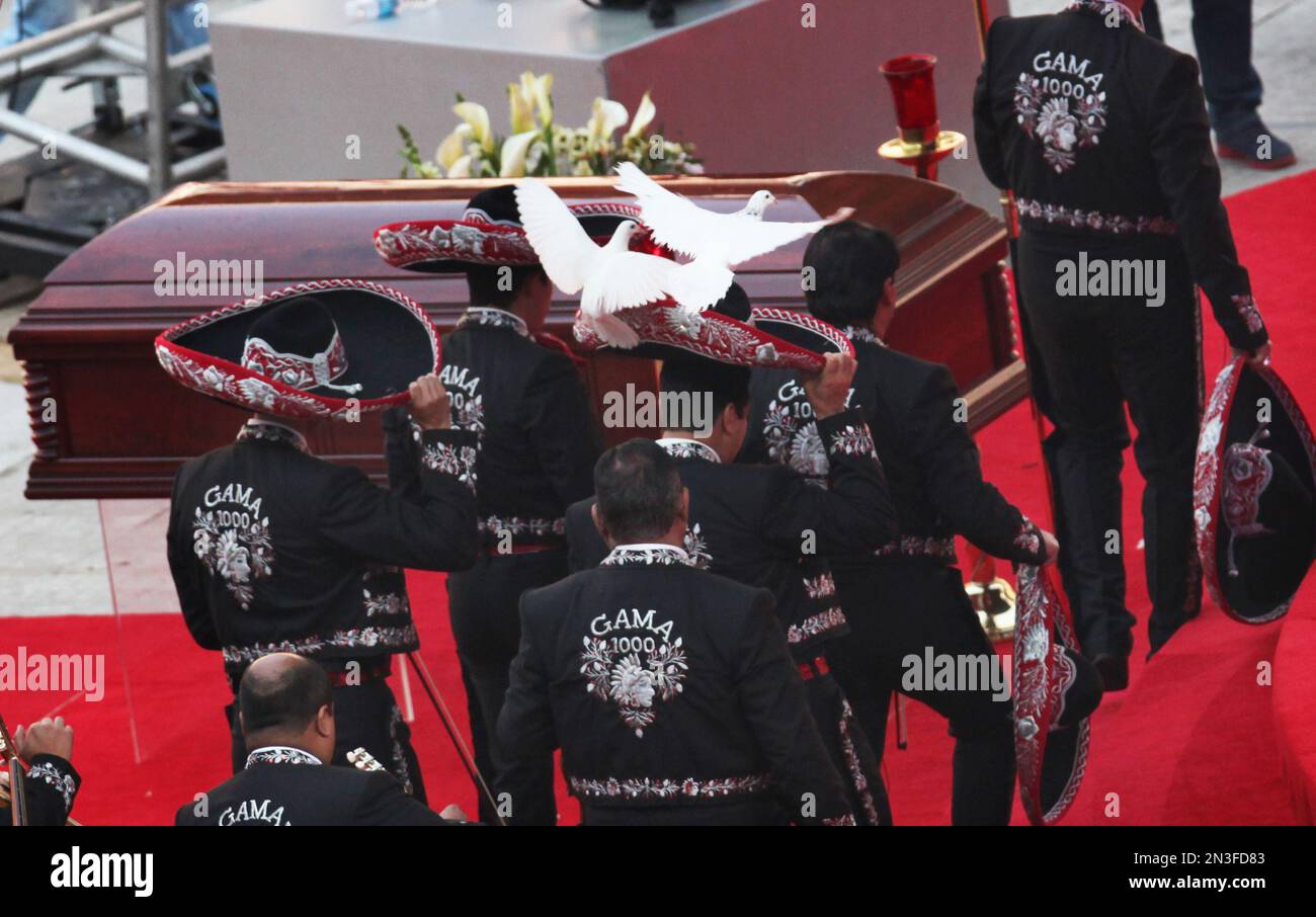 A Mariachi band walks by the casket holding the body of Mexican