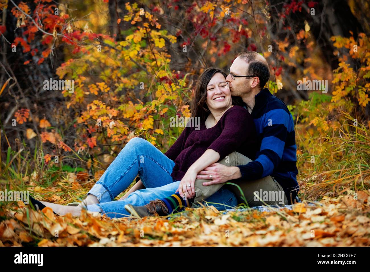 Portrait d'un couple marié mature passant du temps ensemble de qualité à l'extérieur dans un parc de la ville pendant la saison d'automne, le mari embrassant la femme Banque D'Images