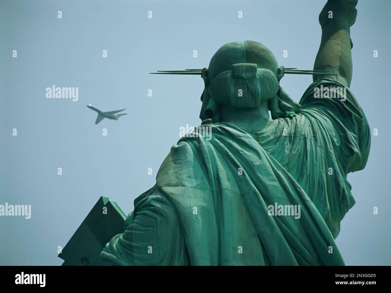 Un avion vole près de la Statue de la liberté dans un ciel bleu vif par une journée ensoleillée ; New York City, New York, États-Unis d'Amérique Banque D'Images