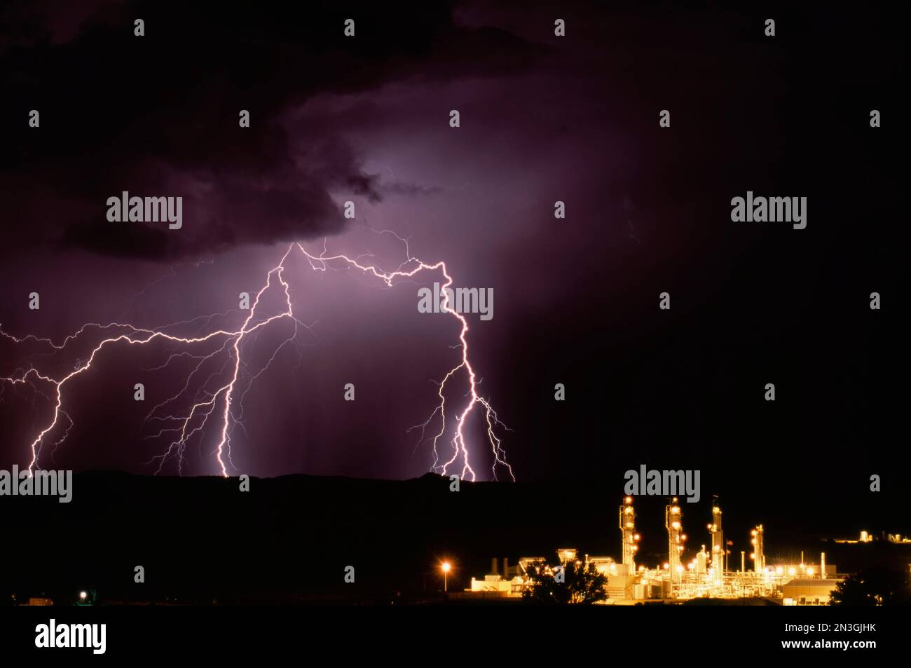 La foudre illumine le ciel nocturne au-dessus d'une raffinerie de gaz ; Bloomfield, Nouveau-Mexique, États-Unis d'Amérique Banque D'Images