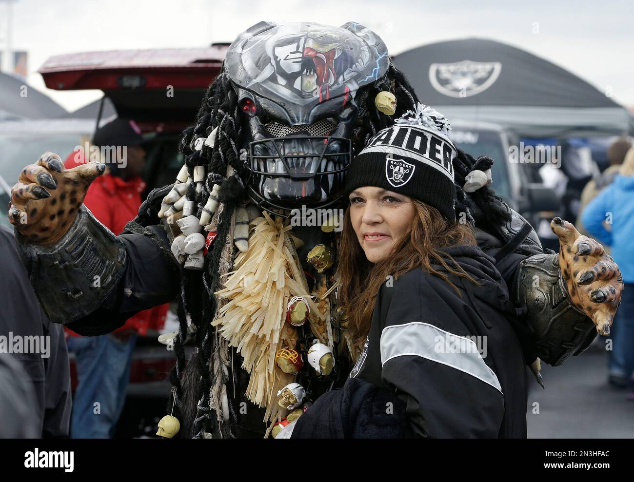 A fan dressed as the Predator poses for photos with an Oakland Raiders fan in the O.co Coliseum parking lot before an NFL football game between the Raiders and the Kansas City Chiefs in Oakland, Calif., Thursday, Nov. 20, 2014. (AP Photo/Ben Margot) Banque D'Images