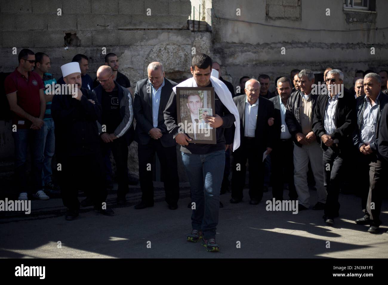 A Druze man holds a photograph of Israeli Chief Inspector Border Police officer Jaddan Assad, in the Druse village of Beit Jann on Mt. Meron in the Galilee, northern Israel, Thursday, Nov. 6, 2014. The officer was killed by a Hamas militant who slammed a minivan into a crowd waiting for a train in Jerusalem, killing one person and wounding at least a dozen before being shot dead by police. (AP Photo/Ariel Schalit) Banque D'Images