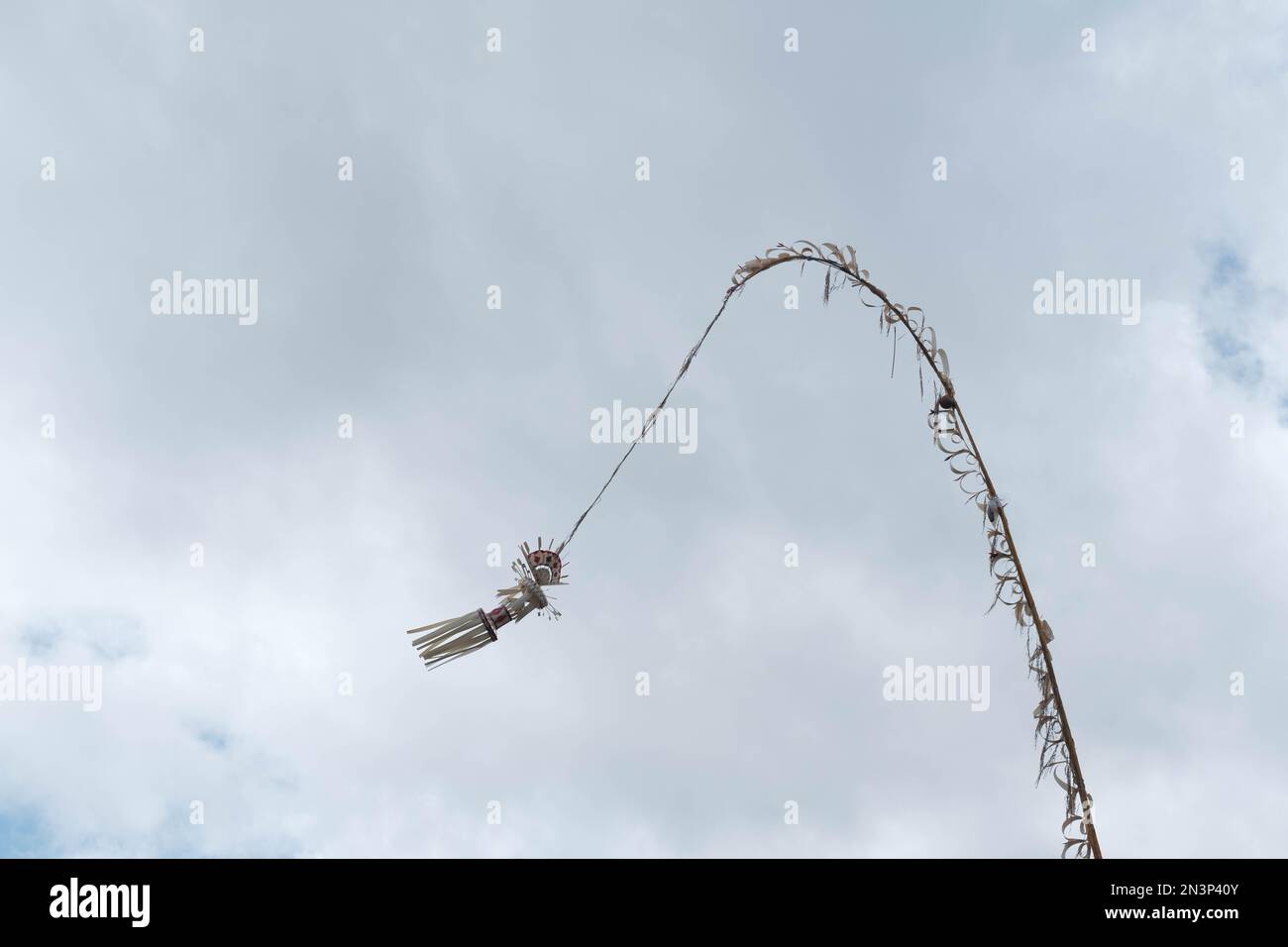 Une décoration balinaise traditionnelle, un Penjor, balançant dans le vent contre un ciel clair et des nuages arrière-plan Banque D'Images