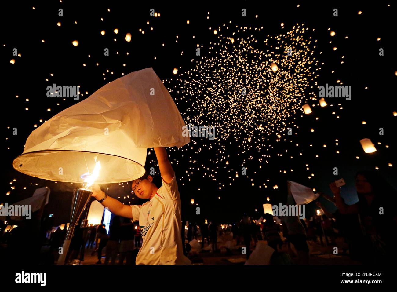 A man holds up a paper lantern before letting it float away at the RiSE Festival Saturday, Oct. 18, 2014, near Jean, Nev. Thousands of people attended the festival and released paper lanterns into the sky. (AP Photo/John Locher) Banque D'Images