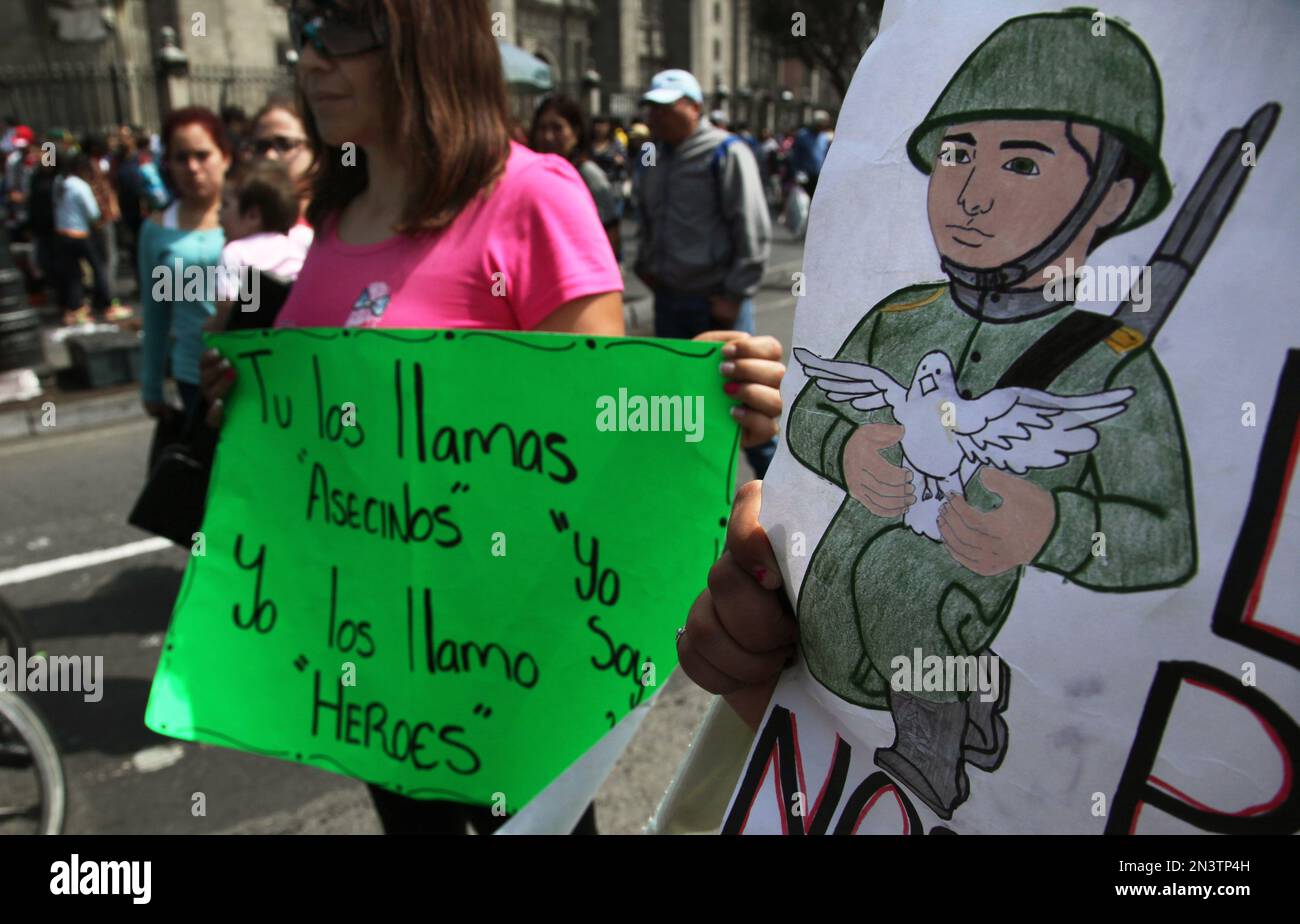 A woman holds a sign in support soldiers who were involved in a shootout that left 22 people dead in Mexico City, Saturday, Oct. 11, 2014. Three soldiers were charged with murder and a lieutenant with a cover up for the events of June 30 in San Pedro Limon, a community in the municipality of Tlatlaya, in the state of Mexico, where 22 alleged criminals were killed that day. The sign at left reads in Spanish "You call them assassins. I call them heroes." (AP Photo/Marco Ugarte) Banque D'Images