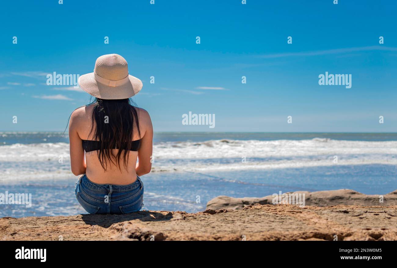 Femme en chapeau de dos à la mer, fille en chapeau regardant la mer, concept de vacances, vue arrière d'une fille regardant la mer Banque D'Images